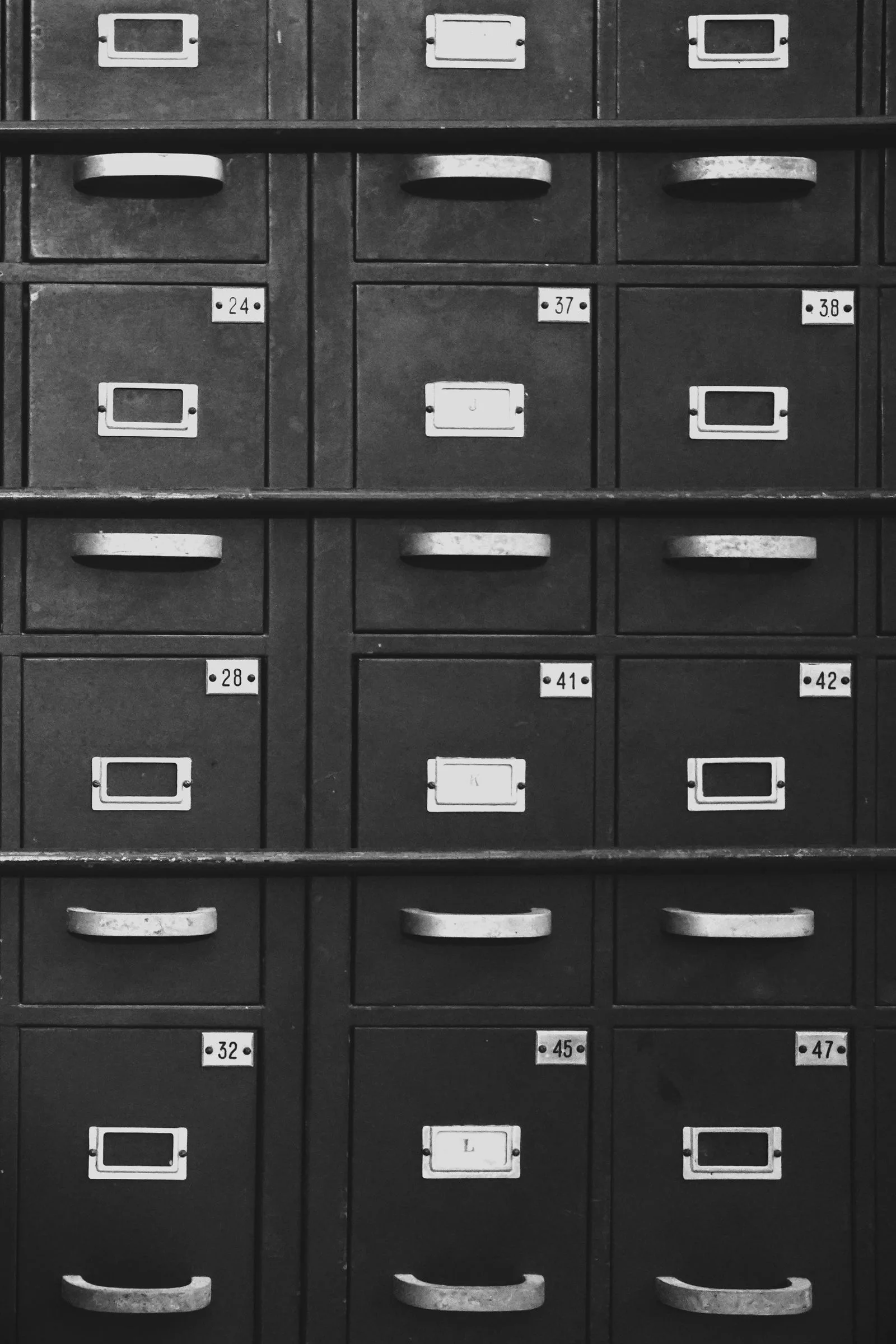 Des rangées de tiroirs d’archives métalliques numérotés dans un ancien atelier gantois.